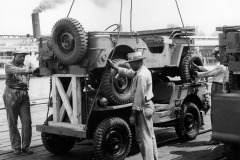 Original caption: "Side view of stacked (double-decked) trucks, 1/4 ton 4x4, on Pier 2, HRPE, before being placed on Liberty Ship Esek Hopkins (HR-438). Official Photograph U.S. Army Signal Corps, Hampton Roads Port of Embarkation, Newport News Virginia."
