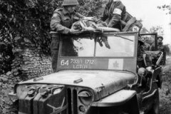 Un aumônier aide un infirmier canadien à évacuer un soldat blessé à bord d une Jeep. 15 juillet 1944  Caen