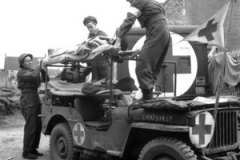 le soldat L.E McKeating, conducteur de la Jeep ambulance, et le soldat L.F. McCadam, 9 C.I.B du 23ème régiment des ambulances de campagne, descend les deux blessés27 juin 1944 BASLY