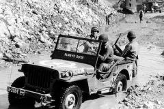 alognes en ruines, photo pris le 24 juin 1944 Une jeep du 298th Engineer Combat Bn de la 1st US Army au premier plan.Place Vicq d Azir et la collégiale Saint-Malo dont le clocher a été dynamité par le génie US car il risquait de s effondrer.A larrière plan, des camions et une pelle mécanique dégagent les décombres pour la circulation des convois militaires vers Cherbourg. 